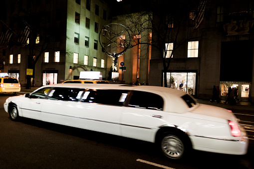 New York, United States - January 14, 2012: White limousine driving in Fifth Avenue in front of the Rockefeller Center in Manhattan New York at night