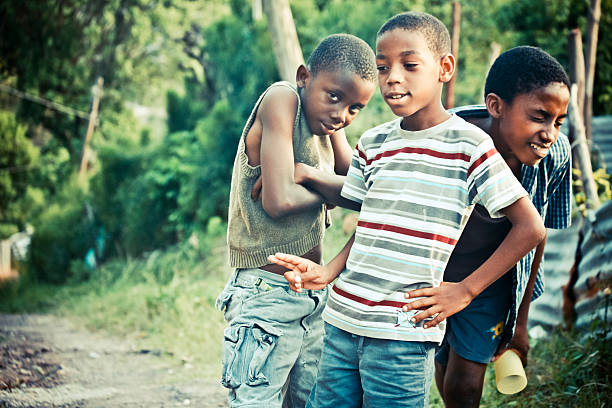 Zanzibar, Tanzania - September 16, 2015: Close-up of young kids from Killimani village raising hands and waiting for a man to give them a lollipop. Tourist who are visiting the village are paying for sweets and let the local man distribute them among them.