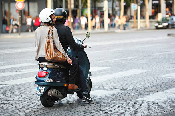 Paris, France - August 9, 2010: young couple on a Vespa LX50 scooter waiting for the traffic light to turn green in Champs Elysees avenue in Paris.