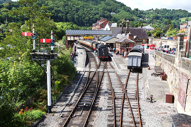 Llangollen, Wales - August 9, 2011: Steam Train at Victorian Railway Station with old Signal Box in Llangollen, Wales. Welsh tourist town with people in the background.