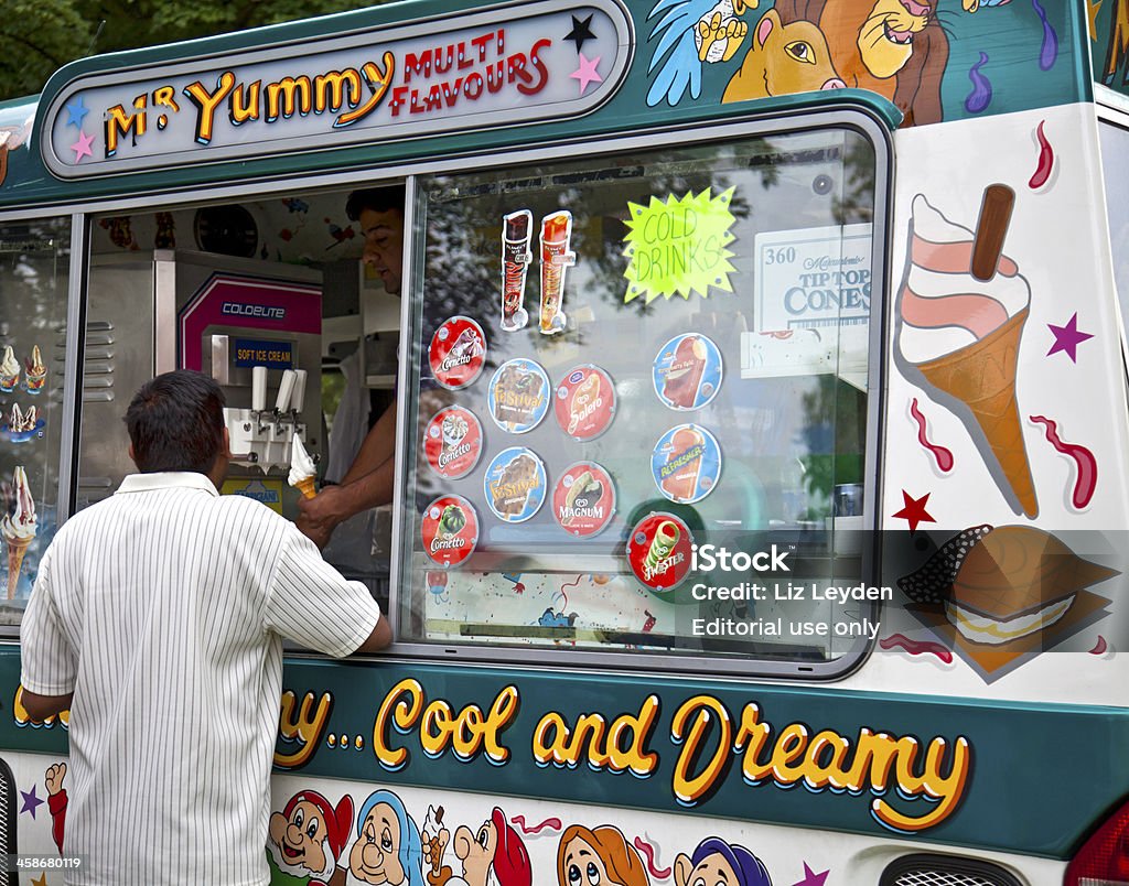 Vendor selling an ice cream cone from a van Edinburgh, Scotland, UK: August 8, 2010: Man buying an ice cream cone from a vendor in an ice-cream van with artwork and stickers representing ice lollies (popsicles). Adult Stock Photo