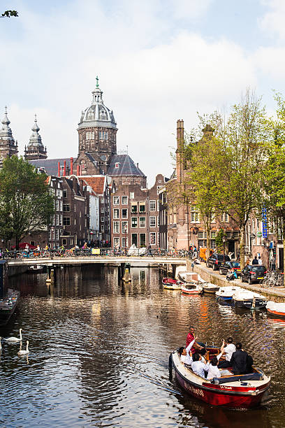 Amsterdam, The Netherlands- August 23, 2011: Japanese tourists visit Amsterdam on a boat sailing along the canals of the city. Amsterdam has been called the \