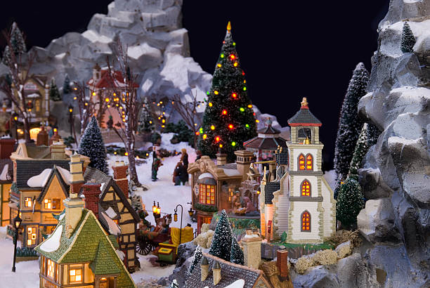 Christmas times in fairy tale town of elf miniature figurines with happy snowman standing while other two persons stacking fishes from harvesting in middle of the village covered in beautiful snows. Christmas scenery.