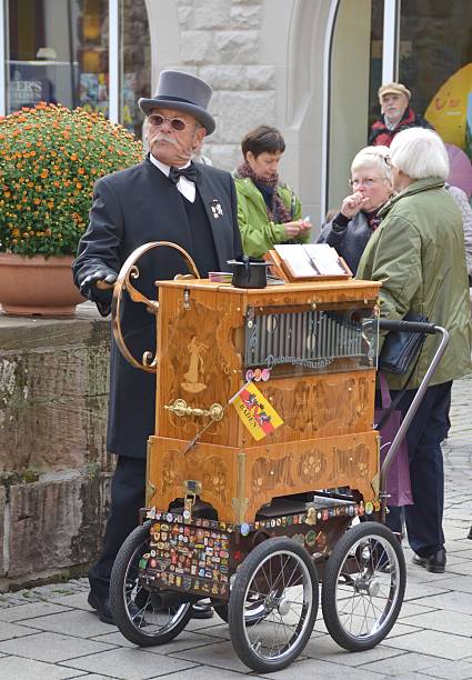 street musician "Lahr, Baden, Germany - October 22, 2011: Unidentified Barrel organ street musician entertaining visitors during the Chrysanthema Flower Festival in Lahr Germany October 22, 2011" hurdy gurdy stock pictures, royalty-free photos & images