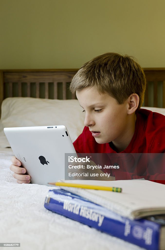 Middle School Boy Using an iPad While Doing Homework Baltimore, Maryland, USA - January 24, 2012: Middle school age boy using an iPad2 while doing his homework in his bedroom. Digital Tablet Stock Photo