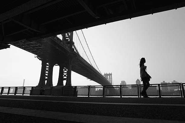 нью-йорк-девушка гуляет для работы под мост манхаттана - east river audio стоковые фото и изображения