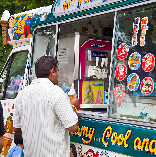 Edinburgh, Scotland, UK: August 8, 2010: Man buying an ice cream cone from an ice-cream van with artwork and stickers representing ice lollies (popsicles). A small child is beside him.