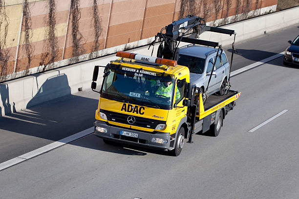 ADAC tow truck Wallau, Germany - February 3, 2012: A male driver in a tow truck of german ADAC Strassenwacht driving on a german highway. The ADAC (Allgemeiner Deutscher Automobil-Club) is Germany's and Europe's largest automobile club and operates a large fleet of mobile mechanics in yellow cars and tow trucks that assist motorists in trouble - the Yellow Angels. Some minor motion blur. Other road users in the background adac stock pictures, royalty-free photos & images