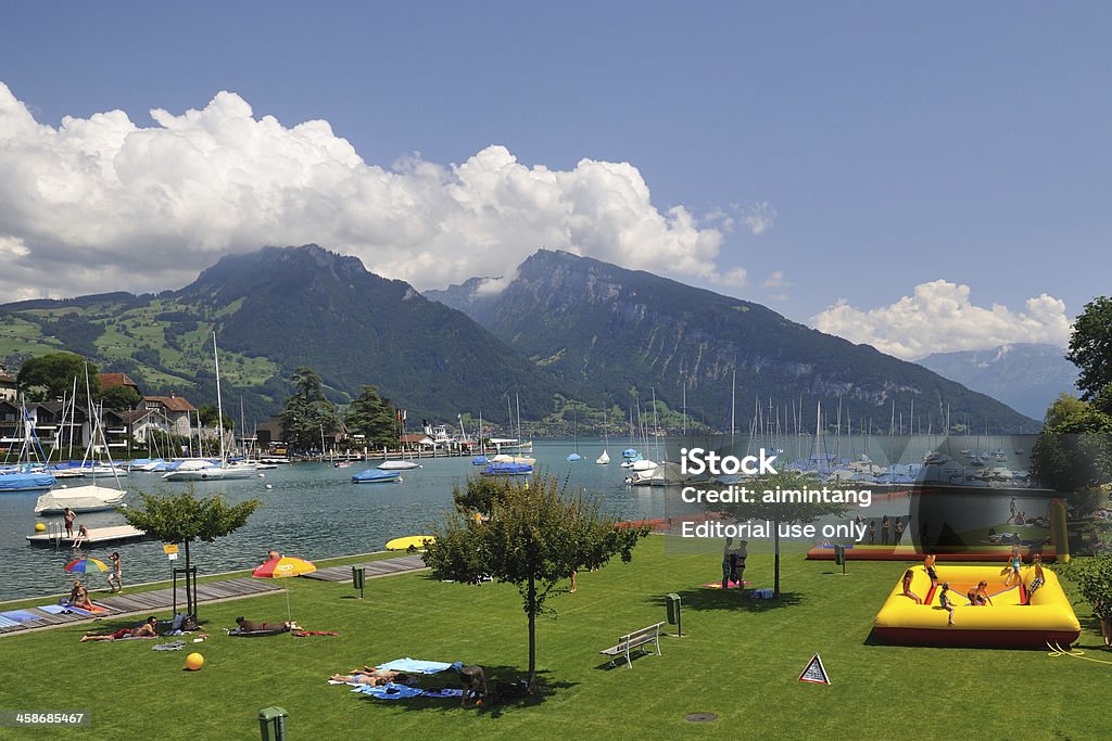 Waterfront Park in Spiez Spiez, Switzerland - July 11, 2011. People enjoy summer time in a waterfront park by Lake Thun in Spiez. Spiez is a small town in the Canton of Bern, famous for its picturesque view of Lake Thun. It is a popular site for tourists in Switzerland. Activity Stock Photo