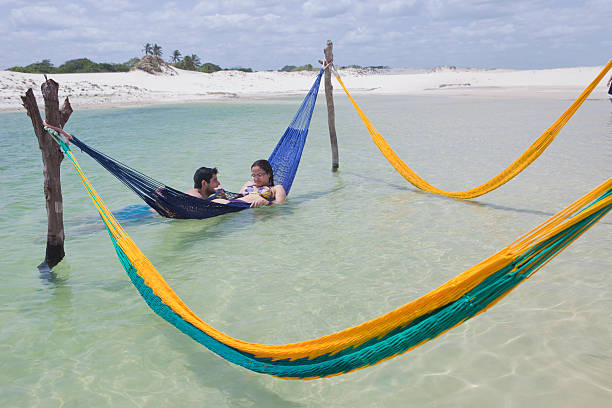 Jericoacoara, Brazil - November 19, 2011: Young couple are having fun on hammock in a beautiful lagoon of Jericoacoara, Ceara, Brazil