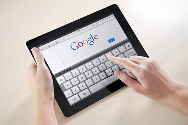 donna mani googling sul dispositivo elettronico - google foto e immagini stock