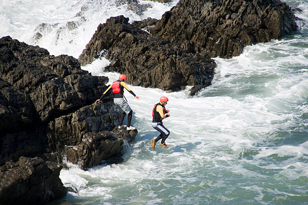 Coasteering in Croyde "Croyde, North Devon, England - June 15th 2009: A man jumping into the ocean. This is part of an extreme sport called Coasteering. Coasteering is a coastal route sport where you will climb, scramble, traverse, swim, go through caves & crevasses, get washed around in the swell, jump and freefall your way to an adrenaline pumping time!" croyde photos stock pictures, royalty-free photos & images