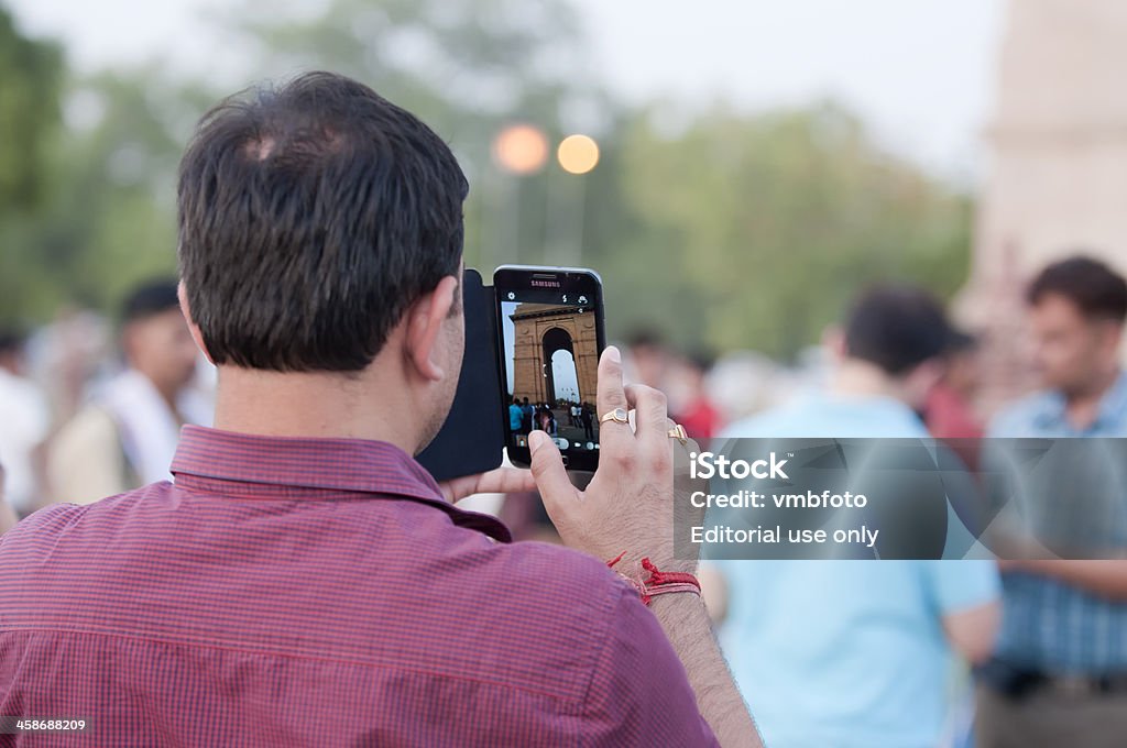 Media Tablet use in India "New Delhi, India - June 23, 2012: An Indian man uses his Samsung Tablet to take a photograph of the India Gate monument. Following the global trend, many Indians have quickly begun using media tablets for daily personal activities." Asia Stock Photo