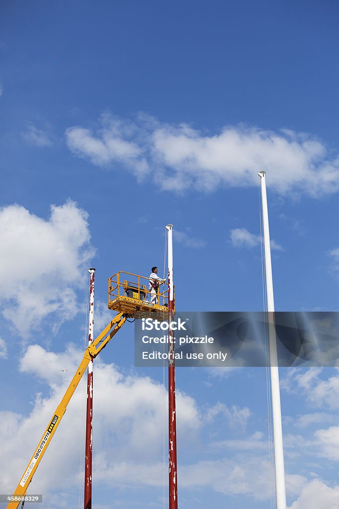 Człowiek na platformę Malowanie flagpoles - Zbiór zdjęć royalty-free (Malować)