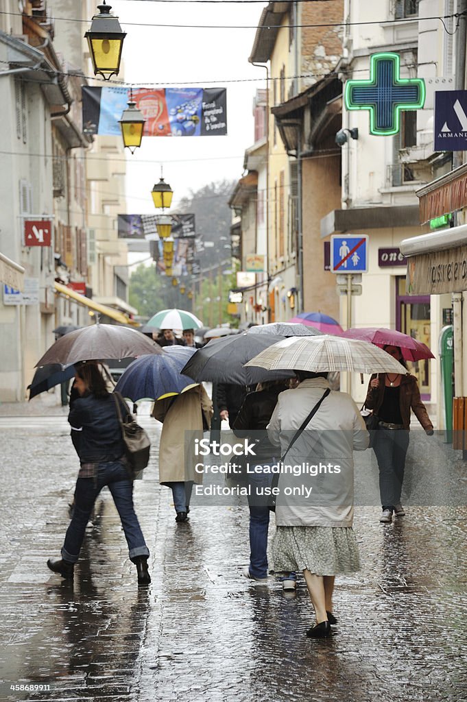 Umbrellas in Annecy Annecy, France - June 8, 2011: Unidentified shoppers and tourists with umbrellas brave the weather on a dismal, wet, summer's day in Annecy, France. The street is the Rue Carnot at the point where it crosses the Rue Sommelier, looking north. Annecy Stock Photo