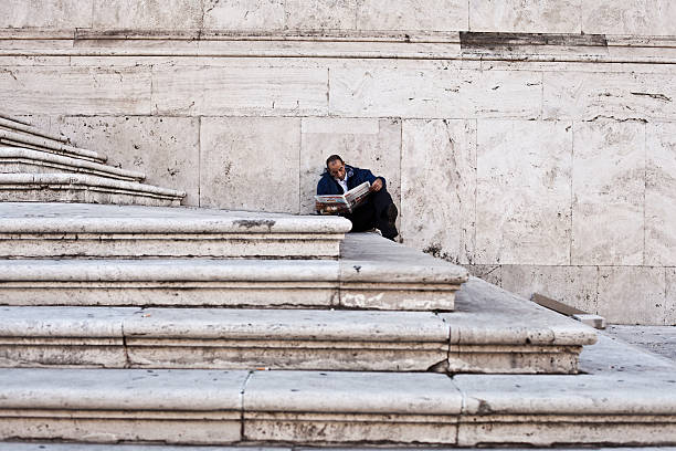 Rome, Italy - October 22, 2011: Adult man reading a newspaper on the stairs of a church in the city center