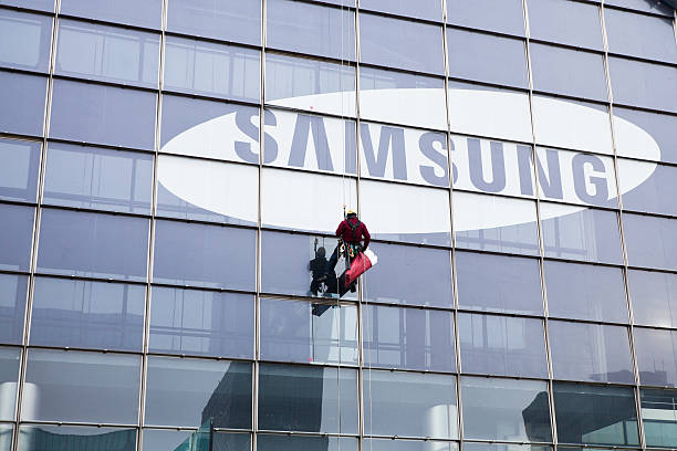 Window Cleaner on a Tall Skyscraper with Samsung Logo Paris, France - January 20, 2012: A window cleaner coming down from a tall skyscraper with the Samsung logo after the end of his work in the business district. steeplejack stock pictures, royalty-free photos & images