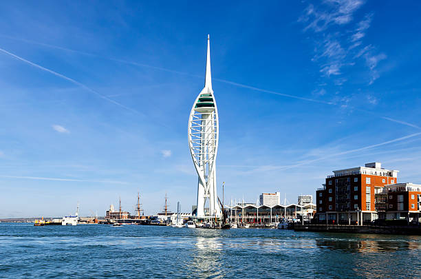 Portsmouth's Spinnaker Tower from Spice Island "Portsmouth, England - October 30, 2012: Portsmouth's Spinnaker Tower seen from Spice Island (Old Portsmouth). The Spinnaker Tower stands in front of a large shopping centre called Gunwharf Quays, built on the site of the former Royal Navy gunwharf. Also visible is the Gunwharf Quays Marina and part of the naval dockyard with administrative buildings, the semaphore tower and HMS Warrior." ironclad stock pictures, royalty-free photos & images