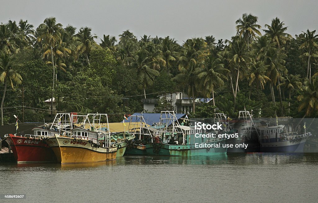 Boats in dock on a river "Kerela, India- August 21, 2011: Fishing boats are docked on a river in Kochi in the Southern India state of Kerela. With 590 km of coastal belt, 400,000 hectares of inland water resources and about 220,000 active fishermen, Kerala is one of the leading producers of fish in India. According to 2003aa04 reports, about 1.1 million people earn their livelihood from fishing and allied activities such as drying, processing, packaging, exporting and transporting fisheries." Trawler Stock Photo