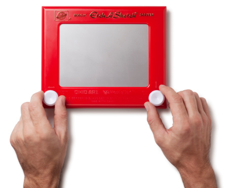 San Diego, California, United States - January 13th 2012: This is an overhead photo of a man starting to use an Etch A Sketch on a white background.  The Etch A Sketch which was created in the 1950s is one of the best known toys of its generation.