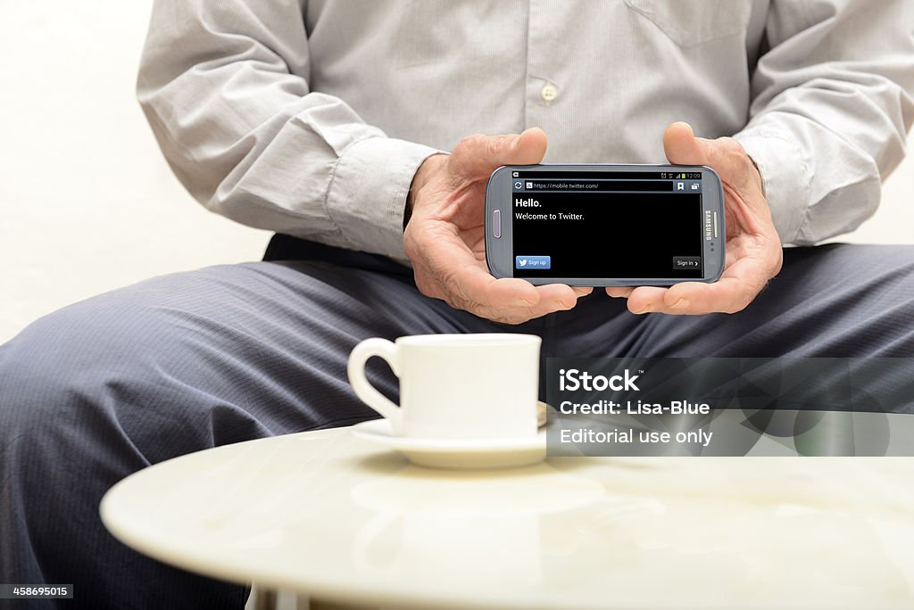 Twitter on Smart Phone "Florence, Tuscany, Italy - November 7th 2012: Man having a coffe while showing his Samsung Galaxi S3 smart phone with the Twitter app on screen" Active Seniors Stock Photo