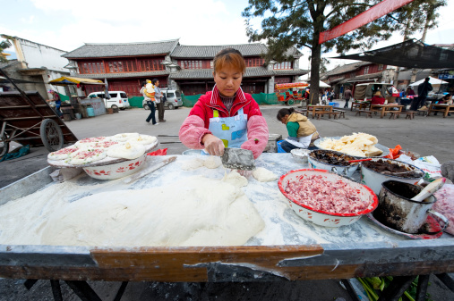 Dali, China - December 13, 2011: A Chinese woman is making cakes on a food stand in street in Dali, Yunnan province, China.
