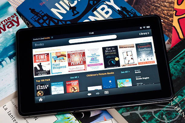 amazon kindle fire schreibtafel auf dem heap der bücher - kindle e reader book reading stock-fotos und bilder