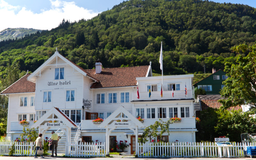 Hardanger, Norway - July 27, 2011: Utne Hotal Hardanger opened 1722. This vintage hotel is beautifully situated by the Hardanger fiord with mountains in the background. A couple of guests are entering the hotel.