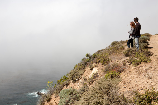 Big Sur, California, USA -August 26, 2011:  A man and a women stand on a hill overlooking the Pacific Ocean in Big Sur, CA