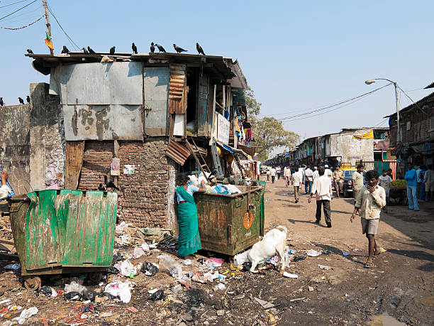 Mumbai, India - January 24, 2008: Dharavi Slum in Mumbai, India. Scene where people can be seen dropping rubbish into some bins on the outskirts of the township. Others are walking past.