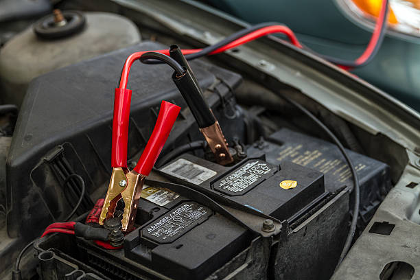 Car Battery with Jumper Cables Miami, Florida, United States – May 21, 2013: Car Battery with Jumper Cables giving load to another car battery. jumper cable stock pictures, royalty-free photos & images