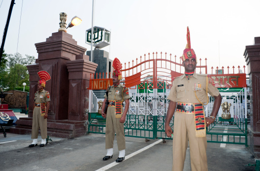 Wagah, Punjab, India - July 10th, 2011: The Indian soldiers after the ceremony called Lowering of the Flags, on the Indian side of the India-Pakistan border. Behind the gates the Pakistani stands for audience can be seen.