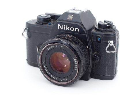 Merion, United States - April 18th, 2010: The Nikon EM SLR with the Nikon Lens Series E 50mm f/1.8 lens attached, isolated on white. It is well used and dusty.