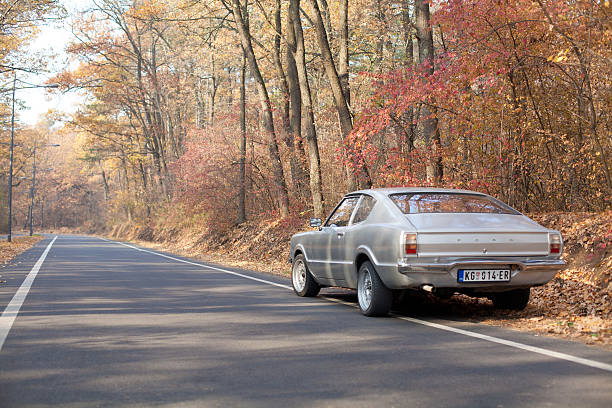 Kragujevac, Serbia - November 17, 2011: Ford Taunus Coupe 1.6 1972 parked in the autumn forest of the city park.This car was developed under the auspices of Ford of Europe and produced in the TC generation from1970 to 1976 year and developed with 2-door coupe body type, RWD (rear-wheel drive) and manual 4-speed gearbox. Petrol (gasoline) engine of 1593 cm3 / 97.2 cui displacement with advertised power 53 kW / 71 hp. Ford Taunus remains a popular car among automobile enthusiasts till today