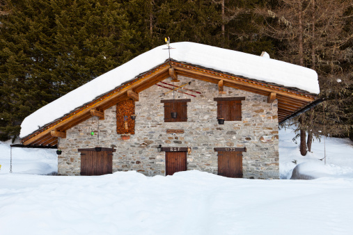 Morgex, Italy- February 7, 2011: traditional mountain chalet surrounded by the snow with skis and poles hanging from the outer wall. It is located in the Valley of Arpy.