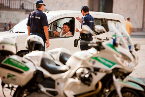 Milan, Italy - September 29, 2011: Driver having trouble with police, Milan, Italy. He entered Piazza del Duomo and police has stopped him. He's holding his Driver License in hands while talking to Police.