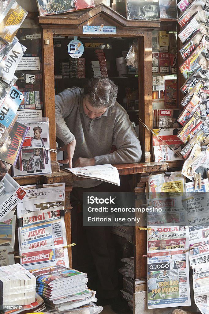 News stand in Lisbon Lisbon, Portugal - December 15, 2011: A vendor standing inside his news stand. This news stand is located in the entrance of the famous coffee shop A Brasileira in Lisbon (Portugal), Rua Garrett 120. Magazine Rack Stock Photo