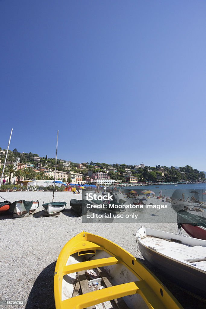 Santa Margherita Ligure in Liguria, Italy - Stock Image "Santa Margherita Ligure, Italy - September 3, 2013: Several sun bathers start to soak up the sun on the beachfront of Santa Margherita Ligure on the Italian Riviera. A yellow boat is included in the foreground." Beach Stock Photo