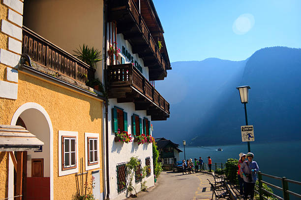 Hallstatt, Austria - 21st July 2010: Korean tourists sightseeing and enjoying the lake view and mountains in front of Haus Cian Holiday Home. Hallstatt, Upper Austria is a village in the Salzkammergut, a region in Austria. Hallstatt is historically known for its production of salt from the local salt mines. The Hallstatt-Dachstein/Salzkammergut region has been listed as part of the UNESCO World Heritage since 1997.
