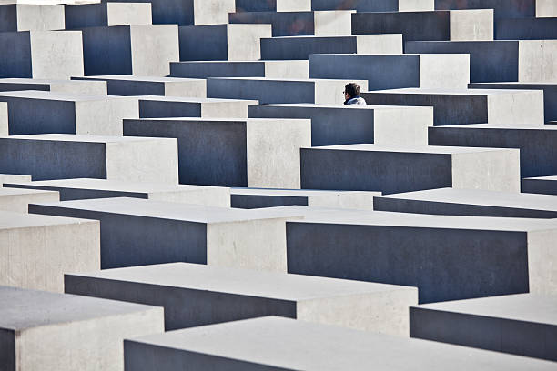 Tourist Visiting Holocaust Memorial in Berlin, Germany Berlin, Germany - November 16, 2011: Man visiting the Memorial to the Murdered Jews of Europe. The memorial consists of a 19,000 square meters site covered with 2,711 concrete slabs or stelae. berlino stock pictures, royalty-free photos & images