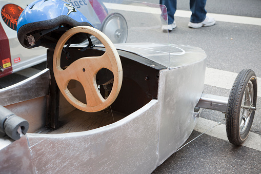 Munich, Germany - July, 25 2010: Each year there is a soapbox car race down the Gebsattelberg (small hill within Munich). Locals are competing for the funniest and fastest vehicles. This image shows a parked silver car with helmet after the race. the steering wheel is made of wood.