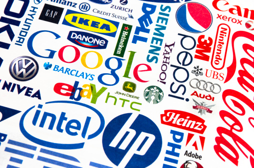 London, England - October 19, 2011: A collection of well-known international brand names printed in a magazine. Names include Ikea, Danone, Google, Gap, Yahoo, Dell, Siemens, Pepsi, 3M, Nintendo, Xerox, Coca Cola, UBS, Audi, Smirnoff, Heinz, Adobe, HP, Intel, eBay, HTC, John Deere, Nivea, Hyundai, VW, Credit Suisse and Heineken. Paper texture and slightly off set registration visible., plus differential focus.