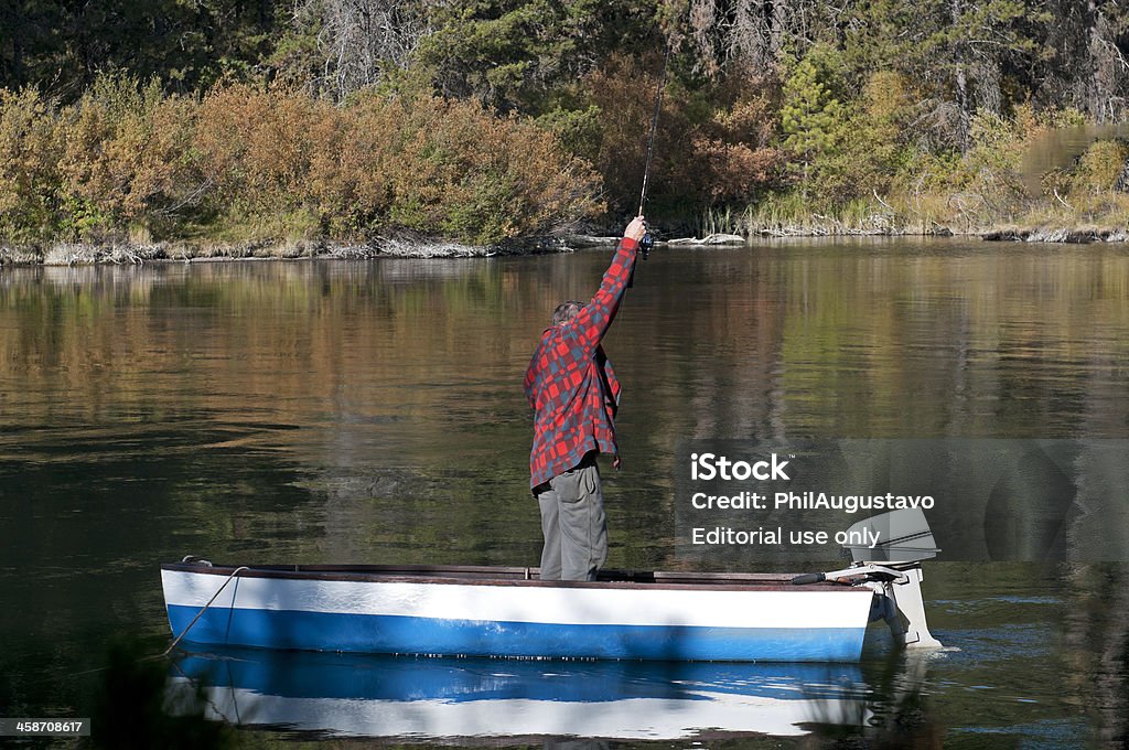 Homme pêche à la truite de rivière en bateau à moteur - Photo de Activité de loisirs libre de droits