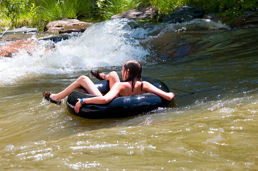 Golden, Colorado, USA - June 20, 2008: Girl in an innertube paddles the whitewater of Clear Creek at the Golden Whitewater Park