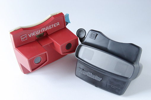 Springfield, Pennsylvania, USA - August 1, 2011: Close up, studio shots, of two different models of View-Masters from the 1970's.  One is red with the logo Gaf (General Aniline + Film Corporation) on it, which is a maker of the View-Master. The other is black and has the word 3D on it.  Both have the word View-Master on them. The View-Masters show the front and back sides of the toy. The View-Master is a children's toy that allows stereoscopic views of reels that create a 3-dimensional image. One can see the levers that are used to change the images on a reel.