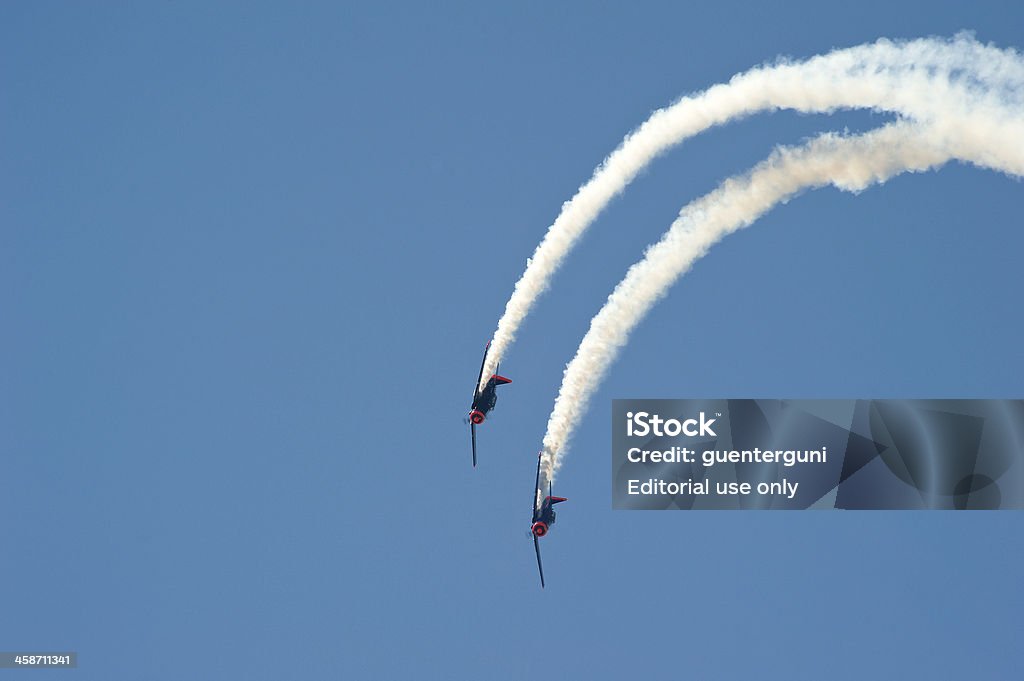 Two historic North American AT6 planes in Red Bull design Wels, Austria - July 11, 2010: Two historic Propeller Aircrafts in the design of Red Bull in a flight formation against the blue sky at the small airshow called Welser Flugtage 2010 in  the town of Wels in Upper Austria. The artifical generated smoke shows their flight route. The planes are North American AT6. This single-engine aircraft was used to train pilots of the US Air Forces, the US Navy and The Royal Air force in the 1930s, in the 1940s (also during World War II) and in the 1950s. Red Bull Stock Photo