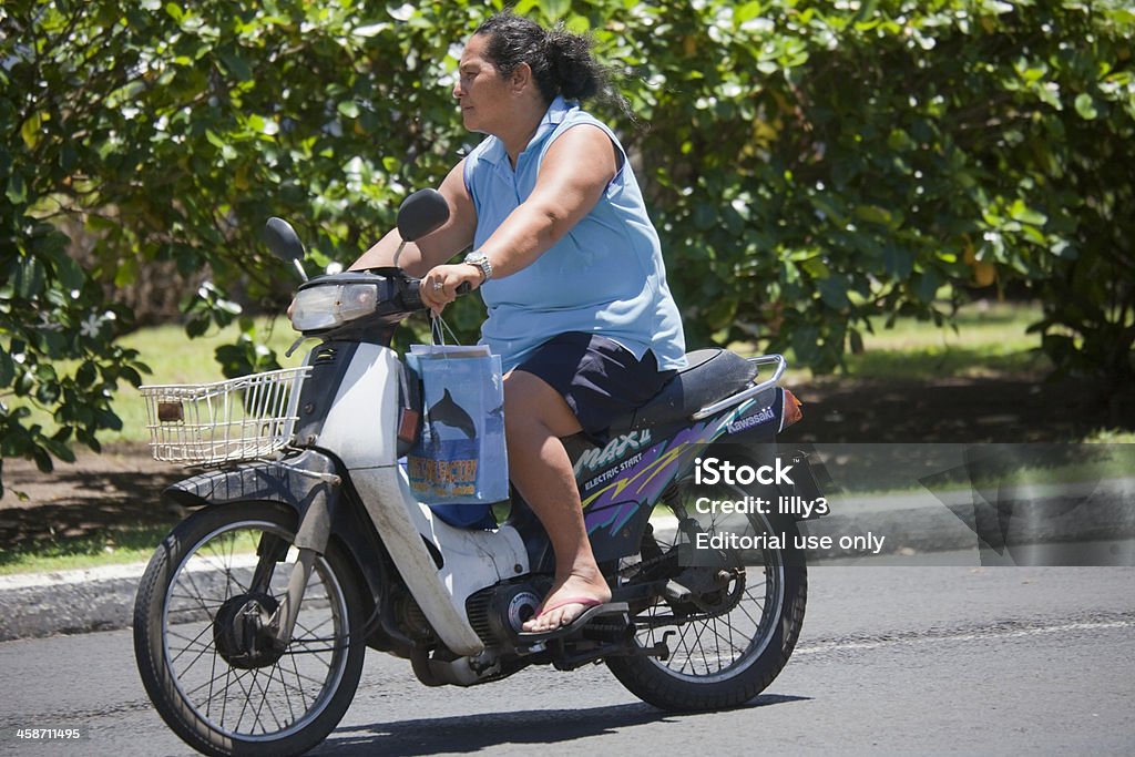 Mature Woman Riding Kawasaki Motorbike "Rarotonga, Cook Islands - February 5, 2009: Mature woman riding Kawasaki motor bike on the main road of the island Rarotonga , Cook Islands. Motor bikes and Scooters are common means of transport for Cook Islanders and for tourists, because the main ring road around Rarotonga named Ara Tapu is only 29 km long." Kawasaki - Kanagawa Prefecture Stock Photo