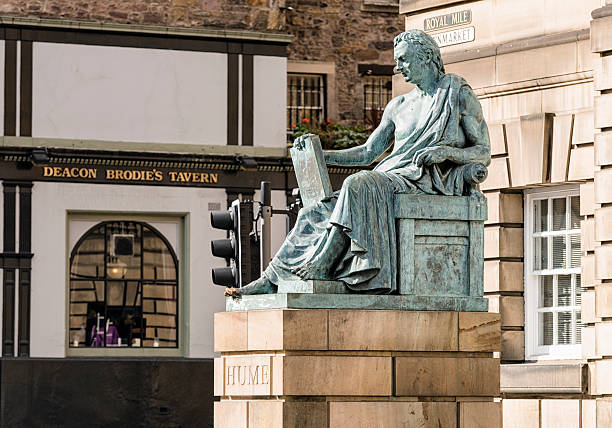 David Hume Statue in Edinburgh Edinburgh, Scotland, UK - September 18, 2013: A statue of the philosopher David Hume (1711-1776), located on the Lawnmarket along Edinburgh's Royal Mile, with Deacon Brodie's Tavern visible in the background across Bank Street. Hume was a central figure of the Scottish Enlightenment and remains one of the most important and influential thinkers in Western philosophy. david i of scotland stock pictures, royalty-free photos & images