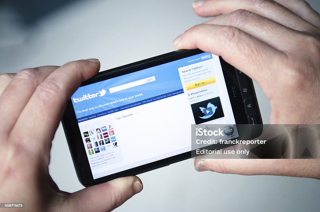 Ręka trzyma smarthphone z twitter.com ośrodka - Zbiór zdjęć royalty-free (.com)
