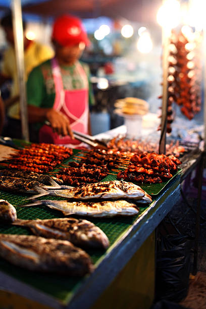 An Asian street food vendor making fried rice at a night market, showcasing popular street food in Malaysia.